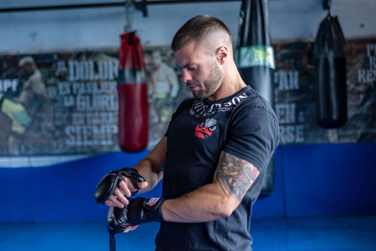 Pratiquant de MMA qui ajuste ses gants d'entraînement en salle