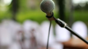 Focused view of a microphone on a stand outdoors, ready for a performance.