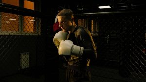 Focused boxer practicing in a dim-lit gym cage, showcasing determination and skill.