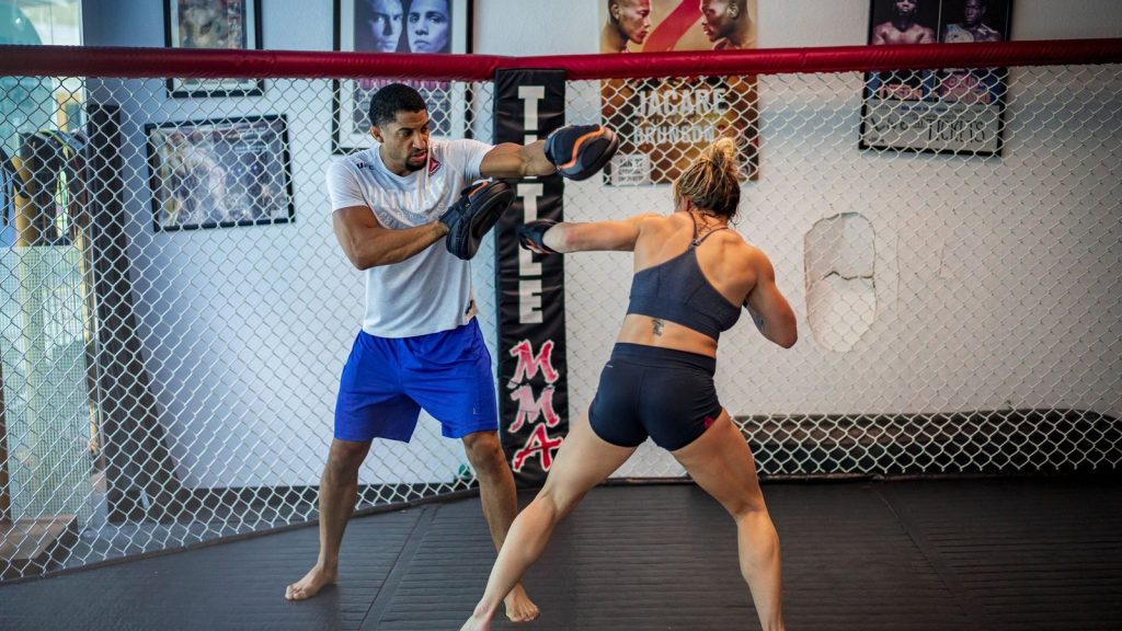 Man and woman in an intense boxing training session inside a gym.