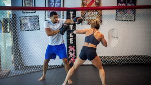 Man and woman in an intense boxing training session inside a gym.