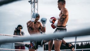 Dramatic outdoor kickboxing match under evening sky with focused athletes in action.
