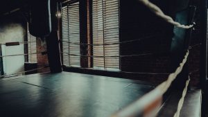 Empty boxing ring in an atmospheric gym with moody lighting and brick walls.