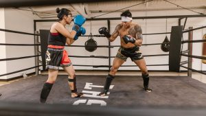 A man and woman engaged in a boxing sparring session in a training ring, showcasing skill and focus.