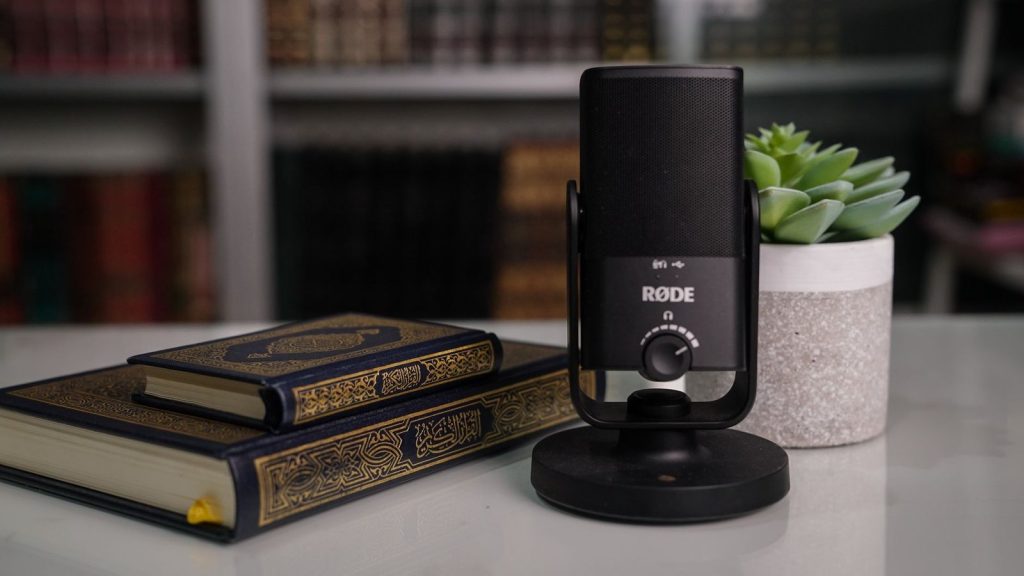 Close-up of books with a Røde microphone and succulent on a desk.