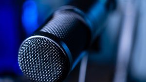Detailed close-up of a professional studio microphone with a blurred blue background.
