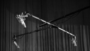 Black and white image of microphones hanging in a studio setting. Perfect for audio production themes.