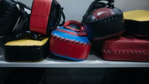 A collection of colorful boxing focus mitts stacked in a gym setting.