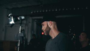 Professional cameraman working on a film set with lighting equipment and camera crew.