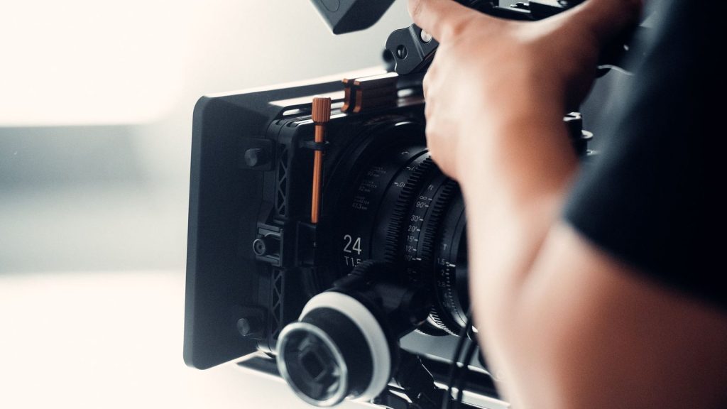 A professional video camera being operated by a person during filming indoors.