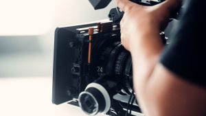 A professional video camera being operated by a person during filming indoors.
