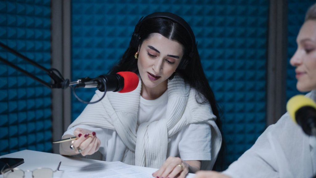 Two women hosting a radio show, using professional microphones in a soundproof studio.