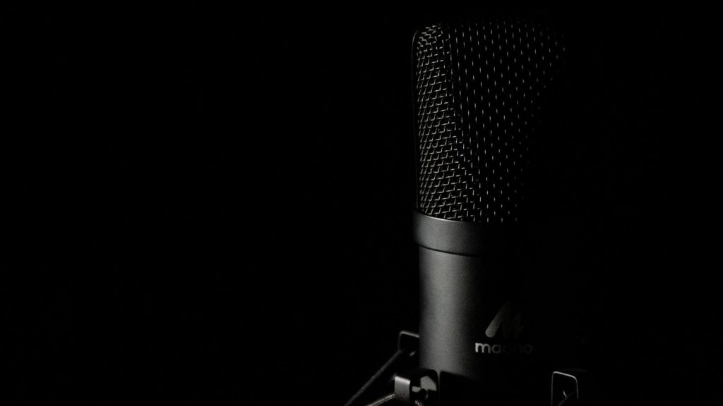 Detailed close-up of a studio microphone with a dark background, ideal for audio production themes.