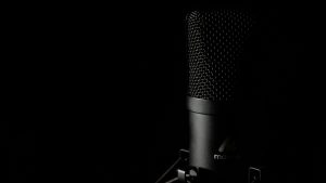 Detailed close-up of a studio microphone with a dark background, ideal for audio production themes.