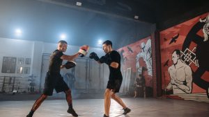 Two men practicing martial arts training in a stylish gym with vivid murals and equipment.