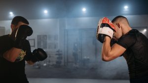 Two men sparring in an indoor gym, focusing on boxing techniques and fitness.