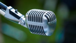 Classic chrome vintage microphone with defocused green outdoor background.