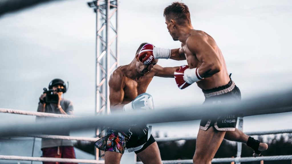 An intense outdoor boxing match capturing a powerful punch between two fighters.