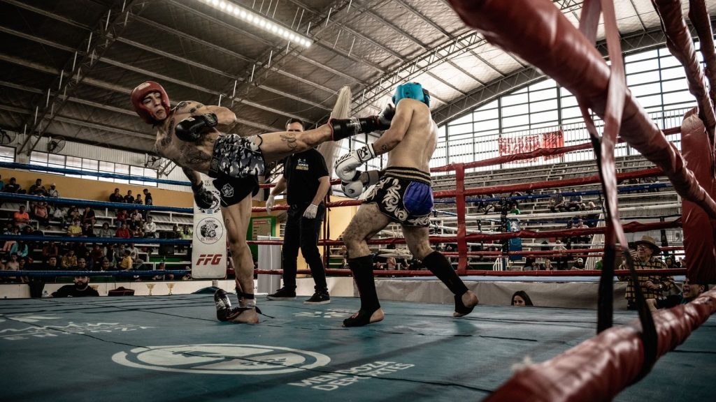 Intense action shot of a kickboxing match inside a packed arena, showcasing athleticism and skill.