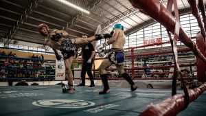 Intense action shot of a kickboxing match inside a packed arena, showcasing athleticism and skill.
