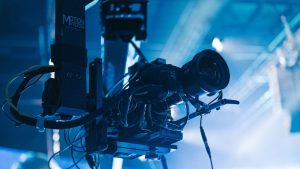Close-up of a professional video camera mounted on a crane arm during a studio filming session.