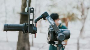 Close-up of a camera mounted on a Ronin stabilizer outdoors, capturing videography equipment in use.