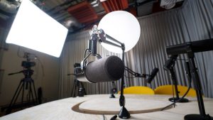 A modern podcast recording studio with microphones, chairs, and lighting equipment.