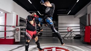 Two men engaged in intense kickboxing training inside a professional ring.
