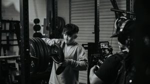 A man focuses while adjusting weights in a gym during weightlifting session captured in monochrome.