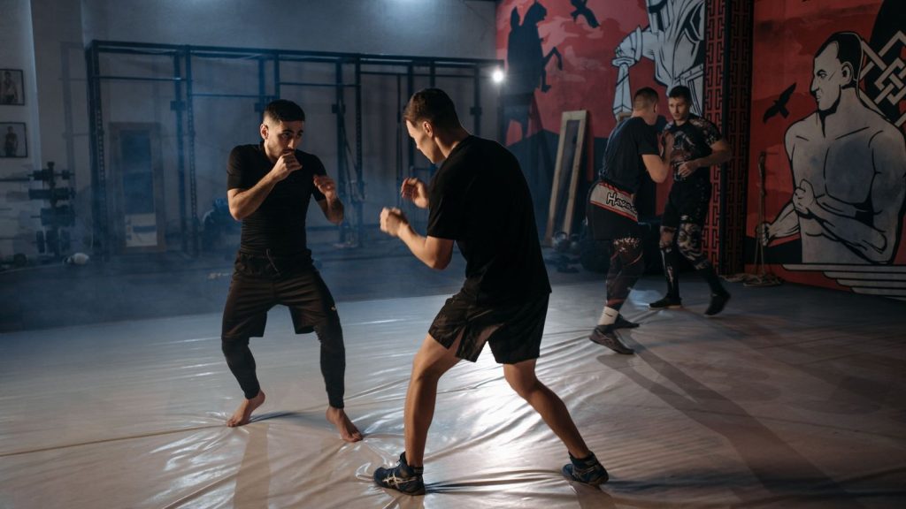 Two martial artists sparring intensely during an indoor training session.