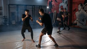 Two martial artists sparring intensely during an indoor training session.