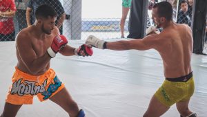 Two competitors engaged in an intense mixed martial arts bout in a cage arena.