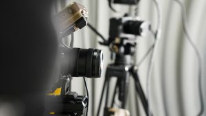 Close-up of professional video cameras on tripods in a studio setting.
