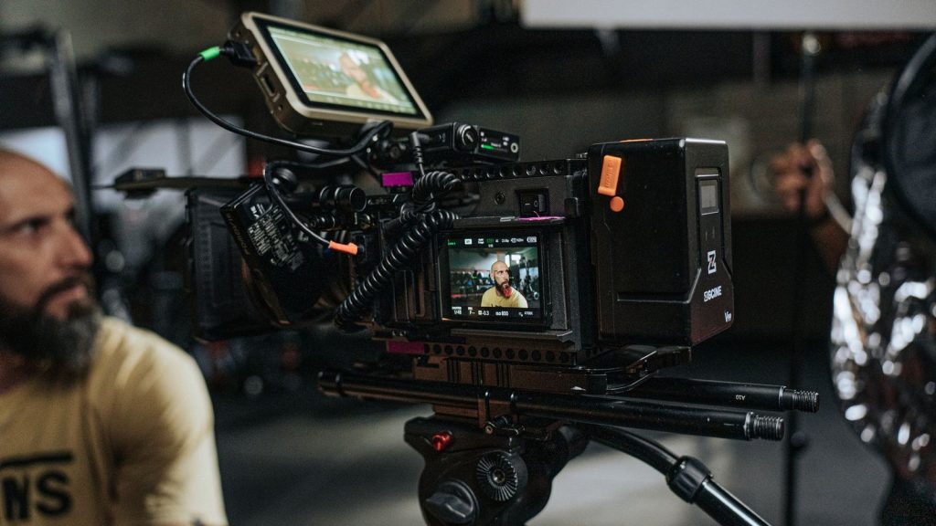 Close-up of a professional film camera setup with crew on a movie set, capturing behind-the-scenes action.