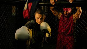 Boxer in white gloves sparring with trainer in a cage fighting ring, martial arts focus.
