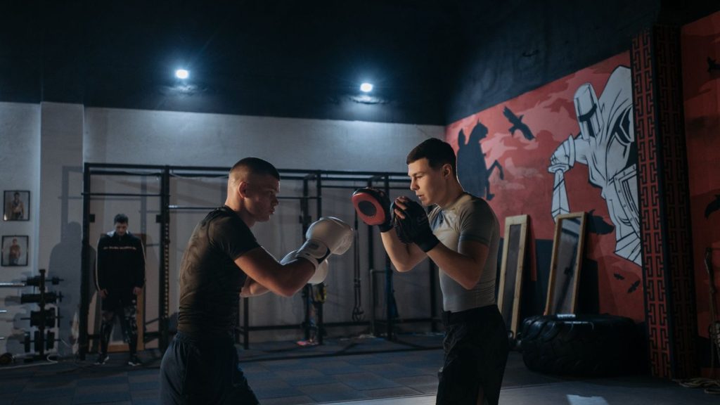 Two men focus on boxing training in an indoor gym, honing combat skills.
