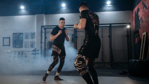 Two men engaged in a focused MMA sparring session in a gym, showcasing skill and technique.