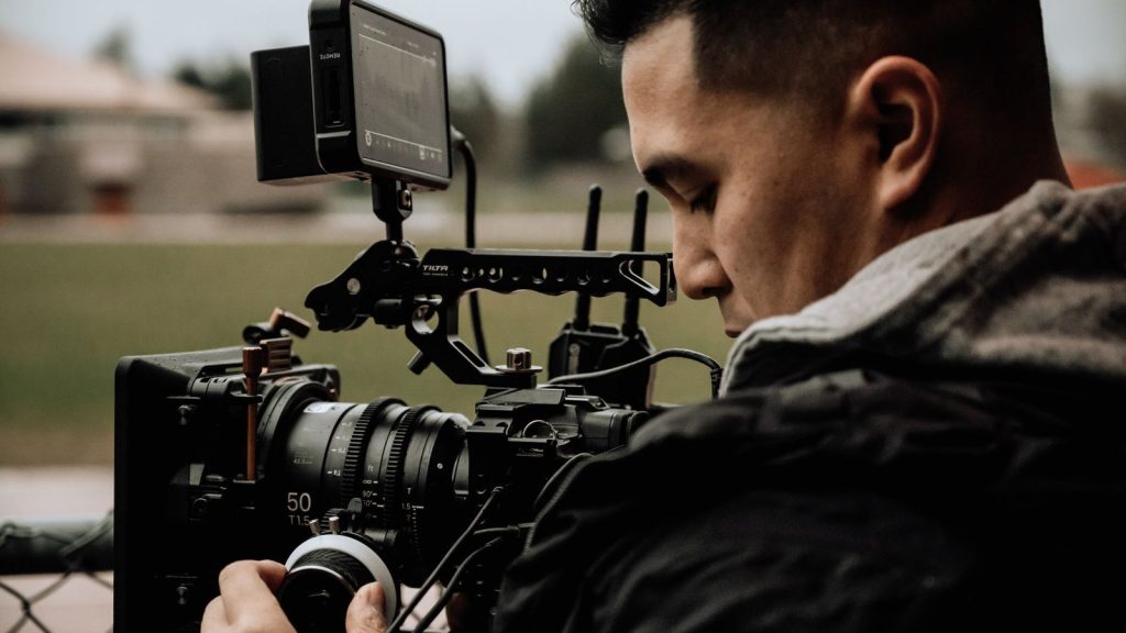 A cameraman using professional equipment for filming outdoors, focused on capturing high-quality footage.