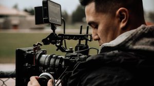 A cameraman using professional equipment for filming outdoors, focused on capturing high-quality footage.