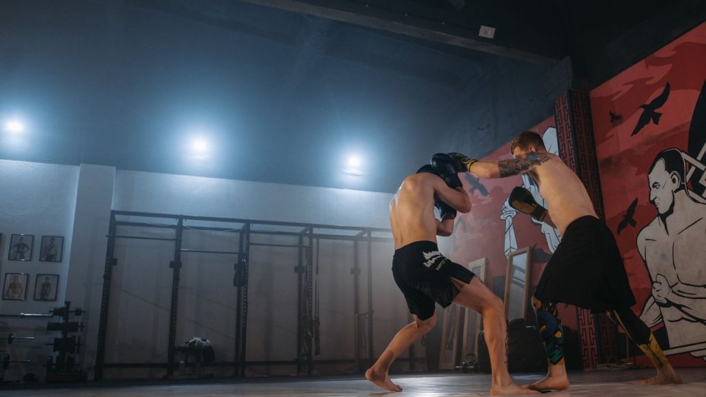 Two MMA fighters sparring indoors, showcasing skill and energy.