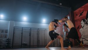Two MMA fighters sparring indoors, showcasing skill and energy.