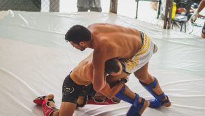 Two fighters engaged in dynamic MMA grappling inside the ring during a sparring match.