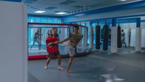 Martial artists practice MMA techniques in a well-equipped indoor gym.