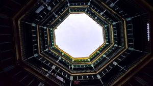 Looking up inside a multi-level octagonal courtyard with dark and light geometric contrasts.