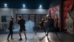 Four men engage in focused MMA sparring in a vibrant indoor gym setting, showcasing combat skills.