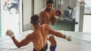 Two male fighters sparring in an indoor gym for martial arts practice.