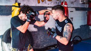 Two young men sparring in a gym, showcasing strength and technique in mixed martial arts training.