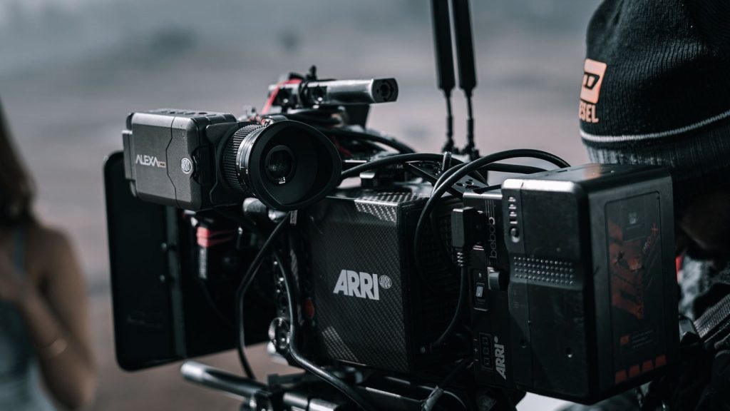 Close-up of a professional filmmaking camera setup on an outdoor set with blurred background.