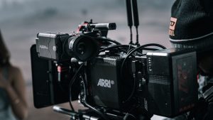 Close-up of a professional filmmaking camera setup on an outdoor set with blurred background.