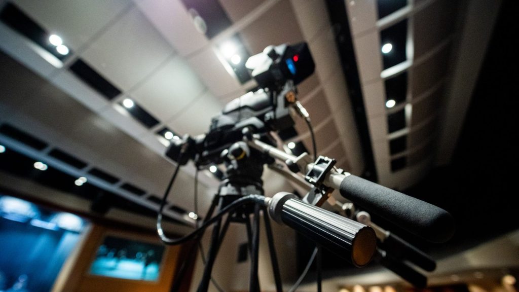 From below of modern professional video camera with wires placed on tripod in studio on blurred background